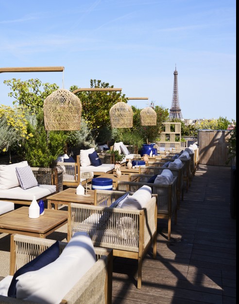 Villa Minuty au Brach Paris : terrasse boisée avec vue sur la Tour Eiffel, mobilier naturel et ambiance méditerranéenne chic.