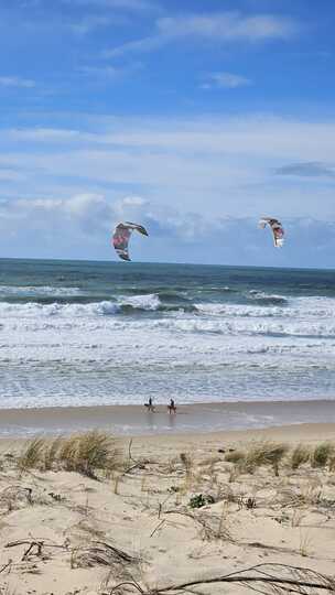 Deux kitesurfeurs sur une plage sauvage du Médoc Atlantique sous un ciel bleu