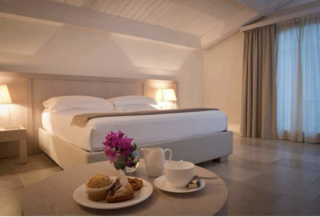 Chambre élégante du Relais Histò, baignée de lumière matinale, avec un petit déjeuner servi dans une atmosphère douce et apaisée.