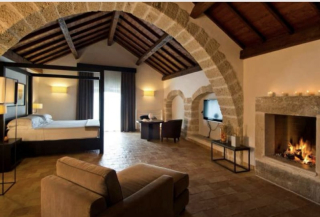 Suite Mar Piccolo du Relais Histò, avec cheminée, voûtes en pierre et plafond à poutres, pour une atmosphère méditerranéenne chaleureuse.
