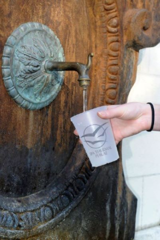 Main tenant un gobelet sous la fontaine d’eau thermale des Thermes de Saujon