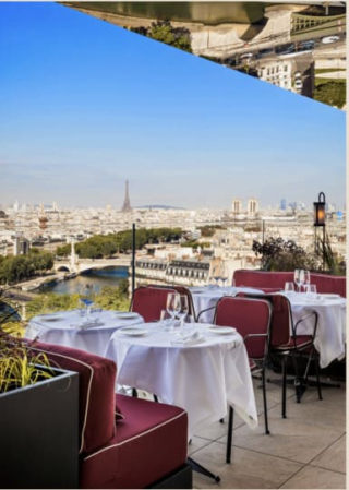 Terrasse extérieure du restaurant Bonnie avec des tables nappées de blanc, des chaises bordeaux et un garde-corps en verre, surplombant la Seine avec la Tour Eiffel au loin.
