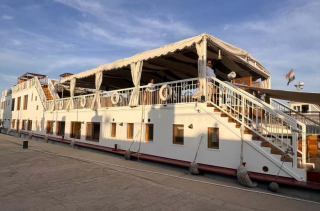 Bateau de croisière sur le Nil avec terrasse couverte, escaliers latéraux et drapeau égyptien.