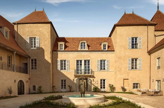 La cour du Château la Commaraine à Pommard, sa façade ocre à deux tours et sa fontaine centrale.