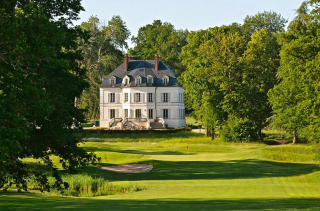 La bâtisse blanche du Domaine du Roncemay dans l'Yonne, entourée d'arbres et dominant un green de golf.